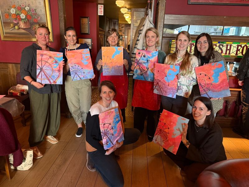 Een groep vriendinnen met hun schilderijen in O'Casey's in Den Haag