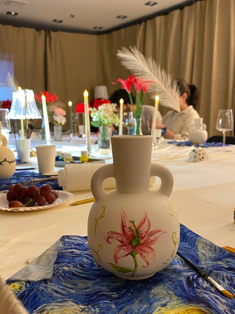 Een beschilderde vaas op een tafel met kaarslicht
