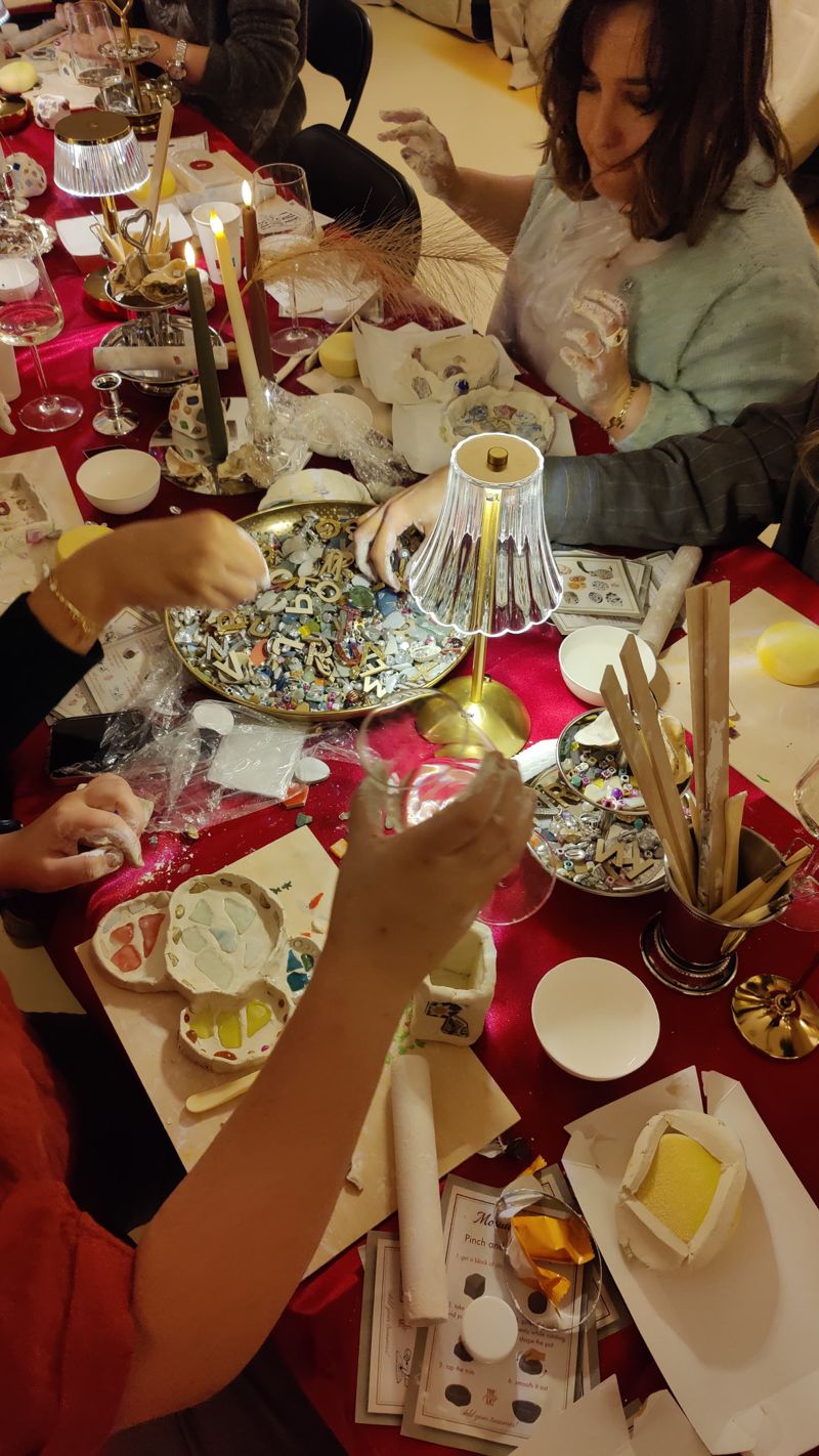 Gasten boetseren met klei aan een tafel met kaarslicht