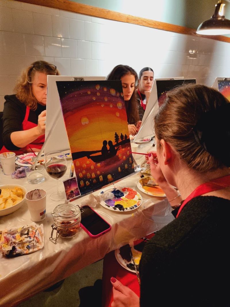 Gasten schilderen een zonsondergang tijdens een avondworkshop