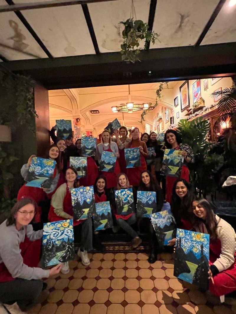 Een grote groep met hun schilderijen tijdens een feestelijke decemberworkshop in Amsterdam